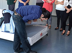 An entomologist demonstrates the inpection of a mattress for bed bugs.