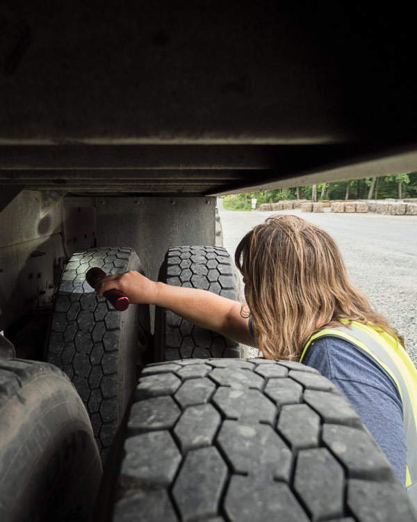 Woman with a flashlight inspecting a truck for spotted lanternfly