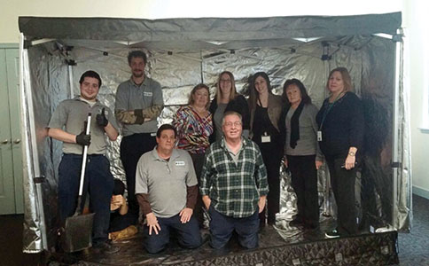 Housing staff pose inside a heat chamber used to kill bed bugs.