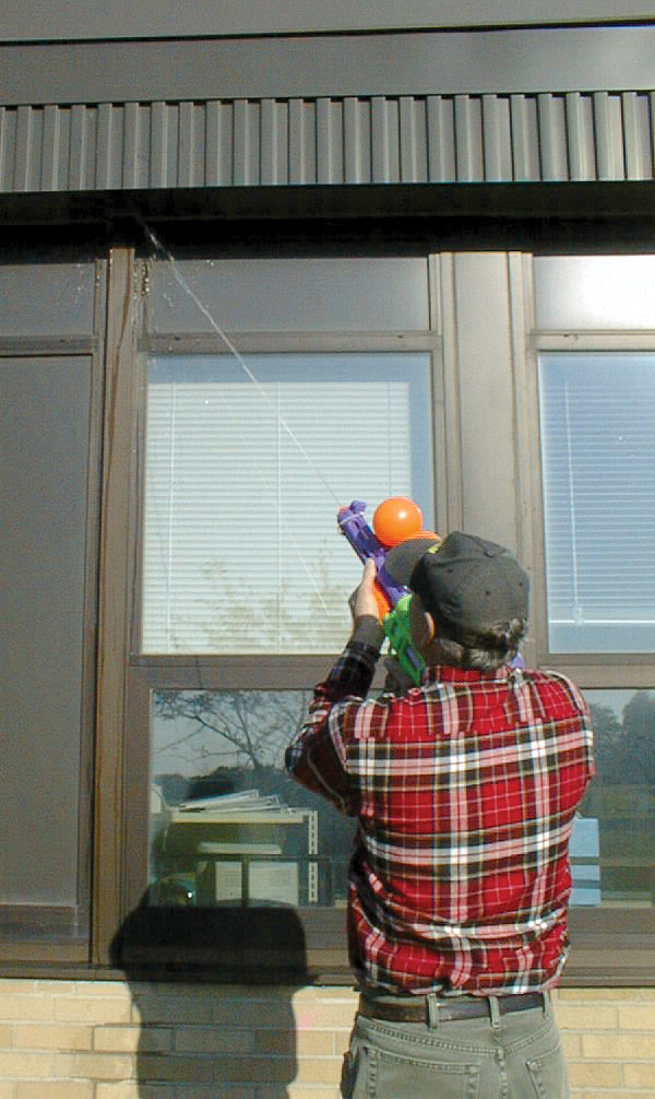 Man using a water gun on a wasp nest