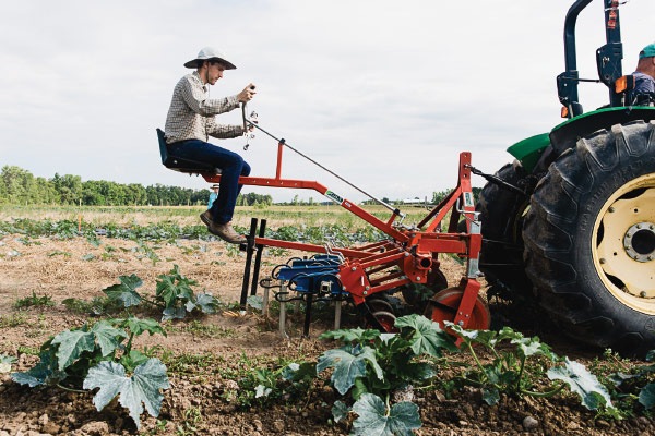 Farmworker operating a mechanical weeder attachment